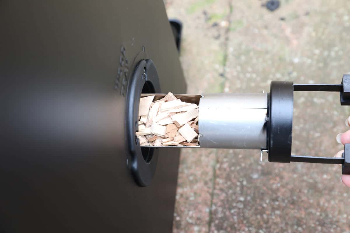 Loading wood chips through the side of a Masterbuilt electric smoker