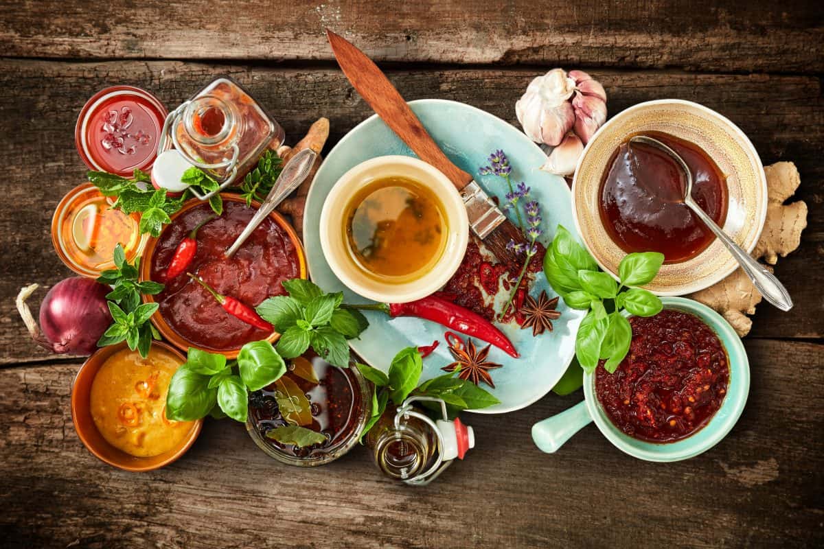 Top view of many different marinades and spices on a ta.