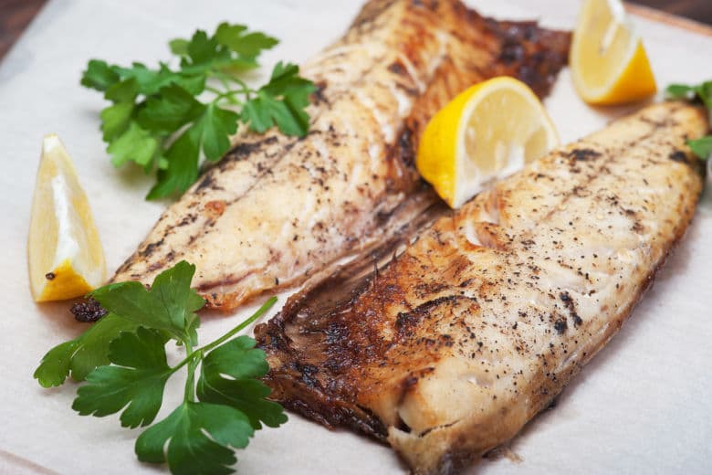 Some fish fillets on a plate with lemon after broiling to create a nice sear