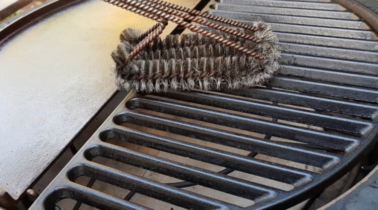 Close up of grill brush cleaning cast iron grill grates