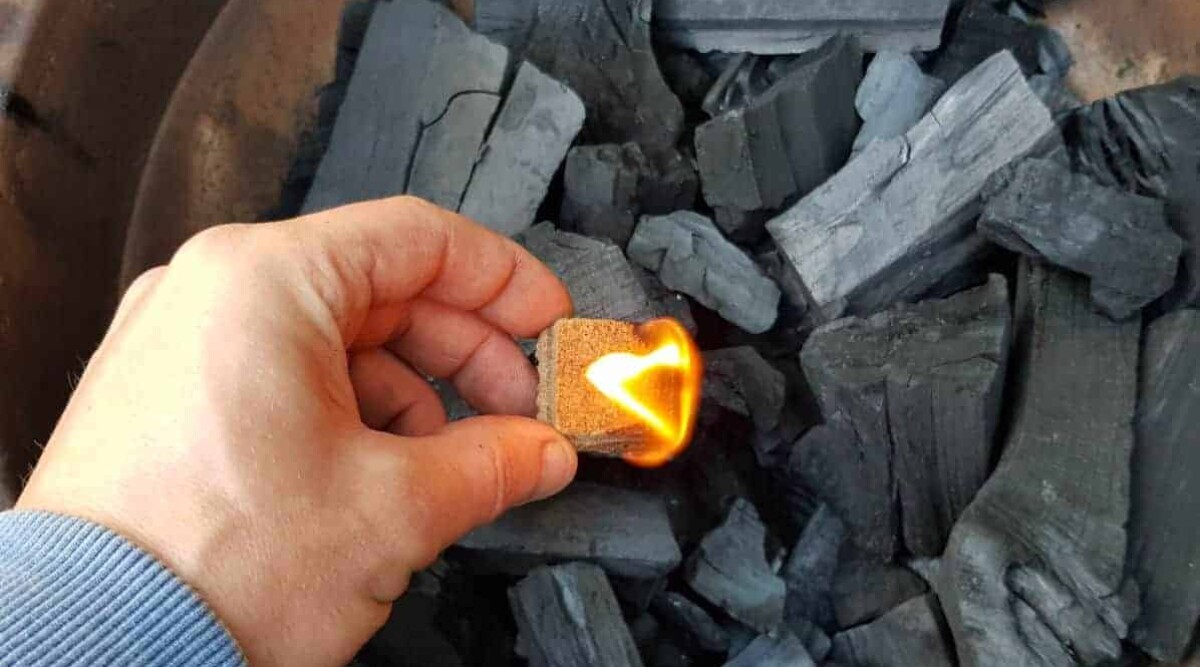 A firelighter being placed into a bed of lump charcoal.