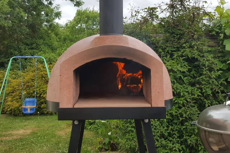 Close up of a wood fired oven with burning logs seen ins.