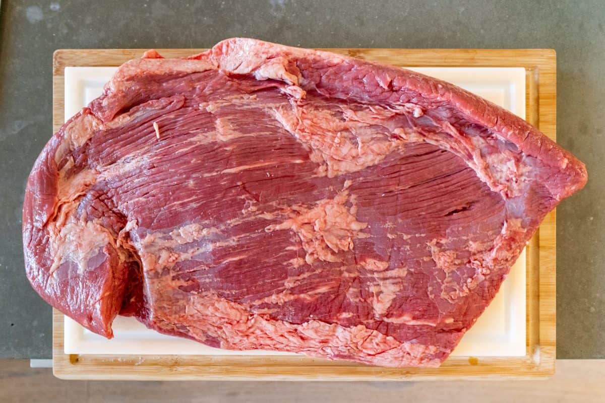 A raw large piece of brisket on a cutting board