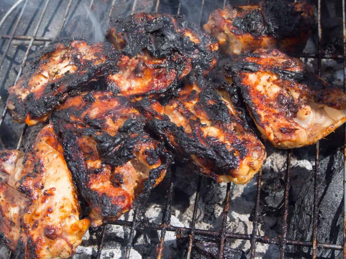 Burnt chicken pieces on a charcoal gr.