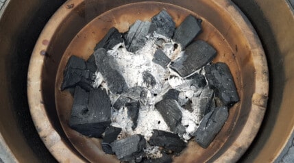 A shot of half burnt charcoal in a kamado Joe fire bowl.