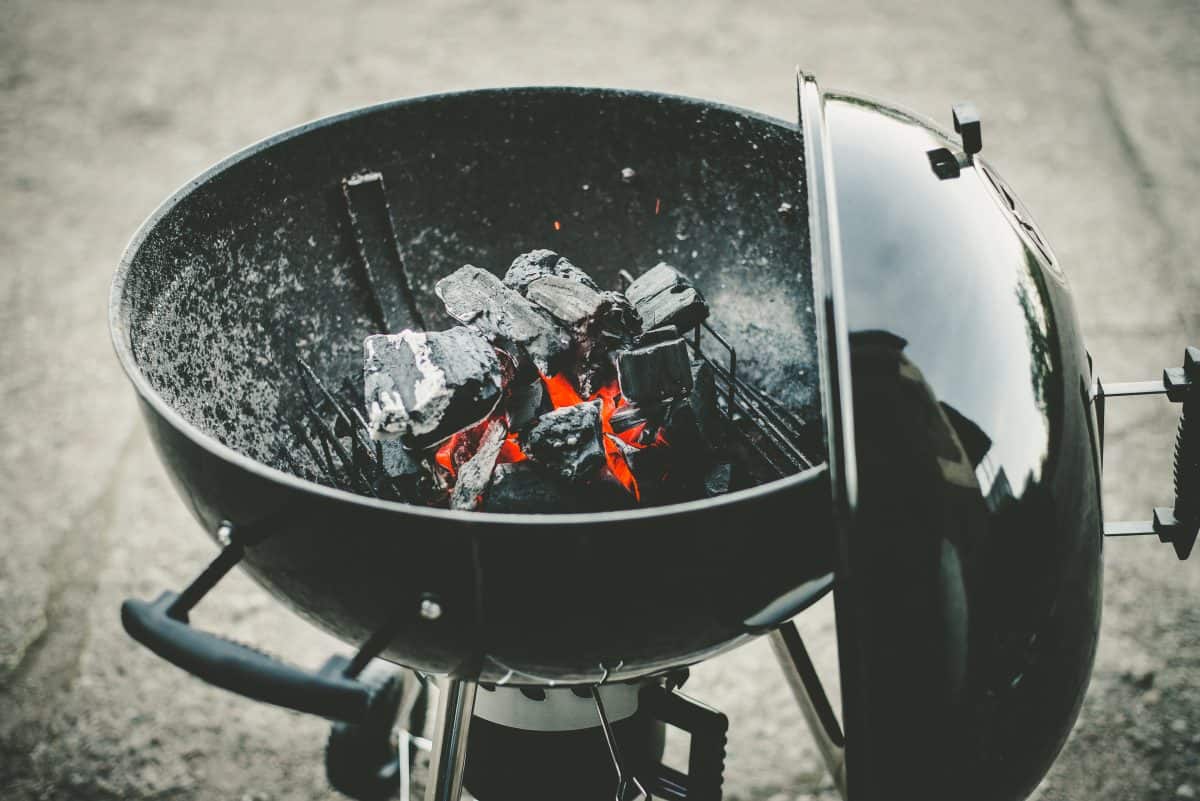 charcoal grill, lid off, with lit lumpwood in the bowl.