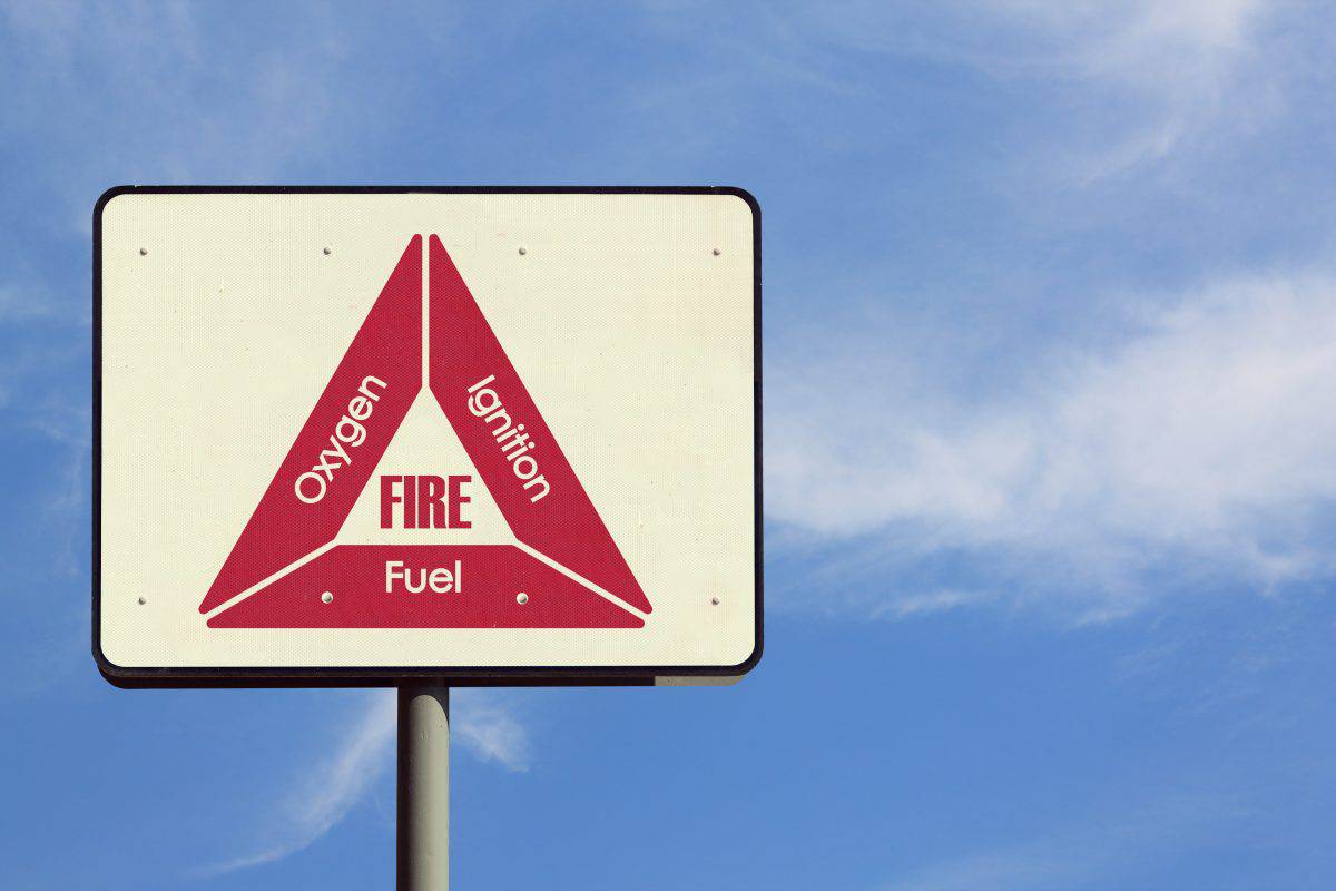 A road sign showing the fire triangle in red on a beige backgro.