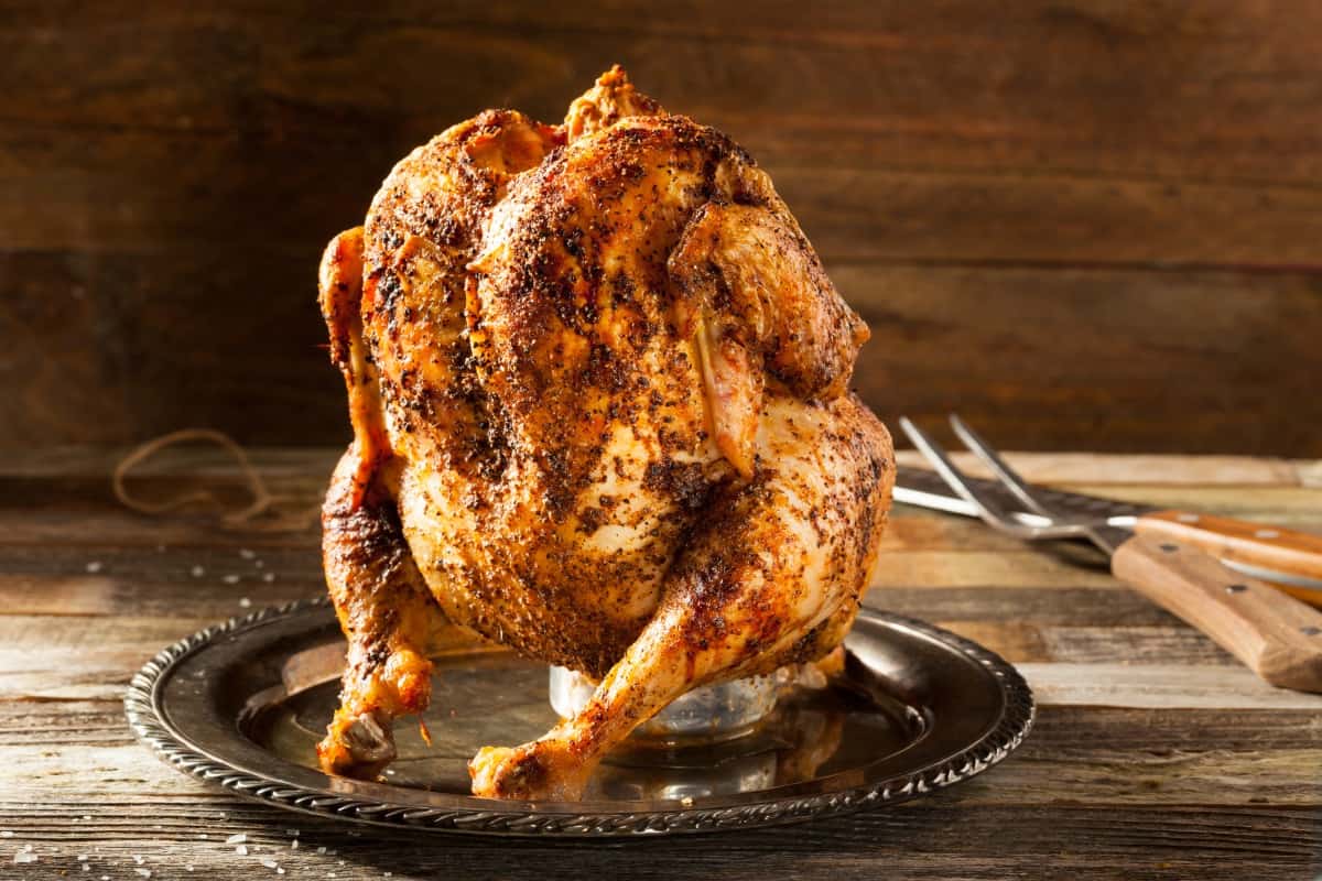 grilled beer can chicken, on a wooden table with a carving knife and fork