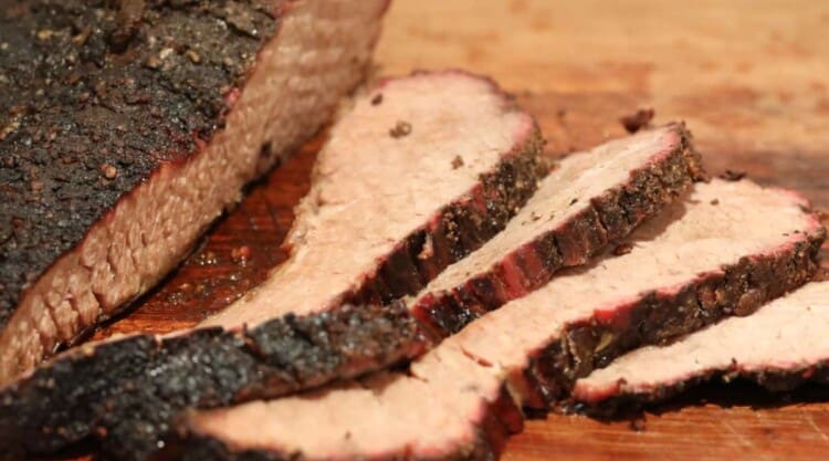 Sliced smoked brisket on a wooden chopping board