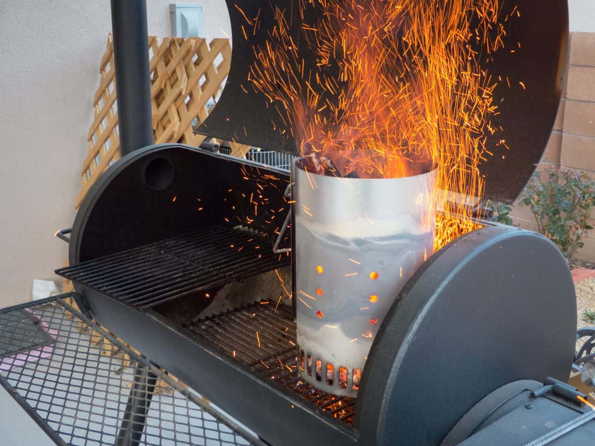 Sparks flying from a lit chimney starter sitting in a barrel type gr.