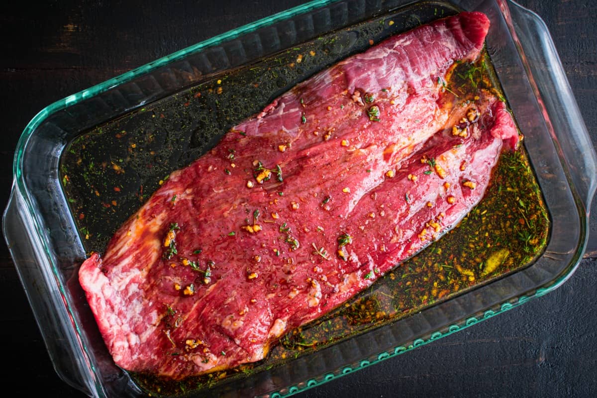 Flan steak marinating in a glass dish