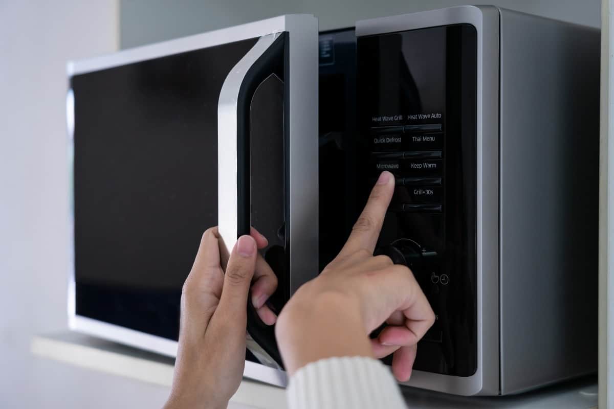  Woman's hands closing microwave door and operating the butt.
