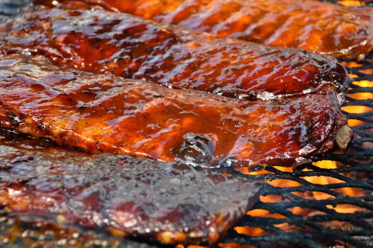 Three racks of ribs on a flaming charcoal gr.