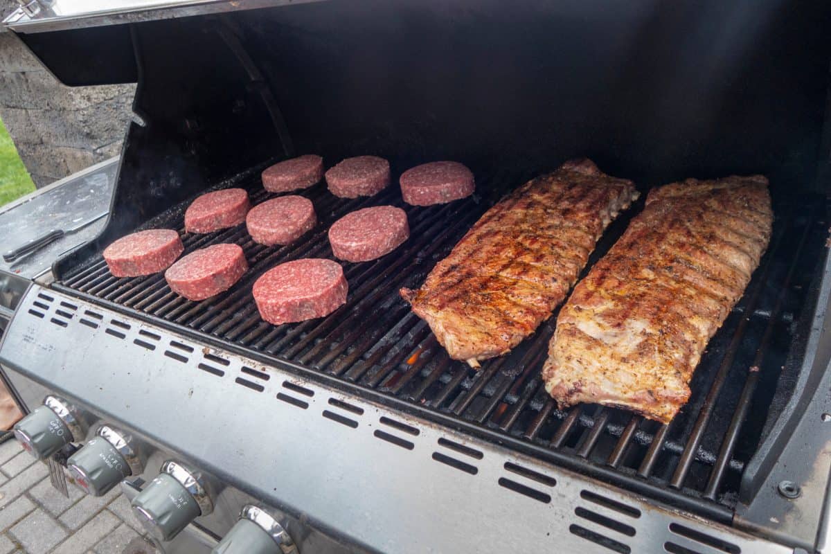 Pork ribs and beef burgers on a gas grill