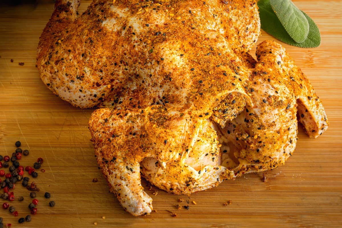 A dry rubbed whole chicken on a cutting board