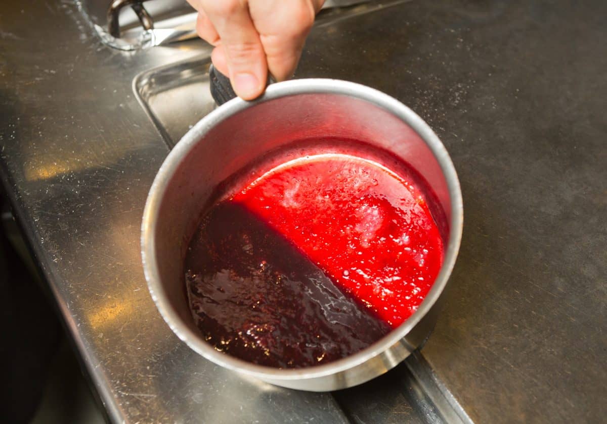 A pan of red sauce being reduced on a hob