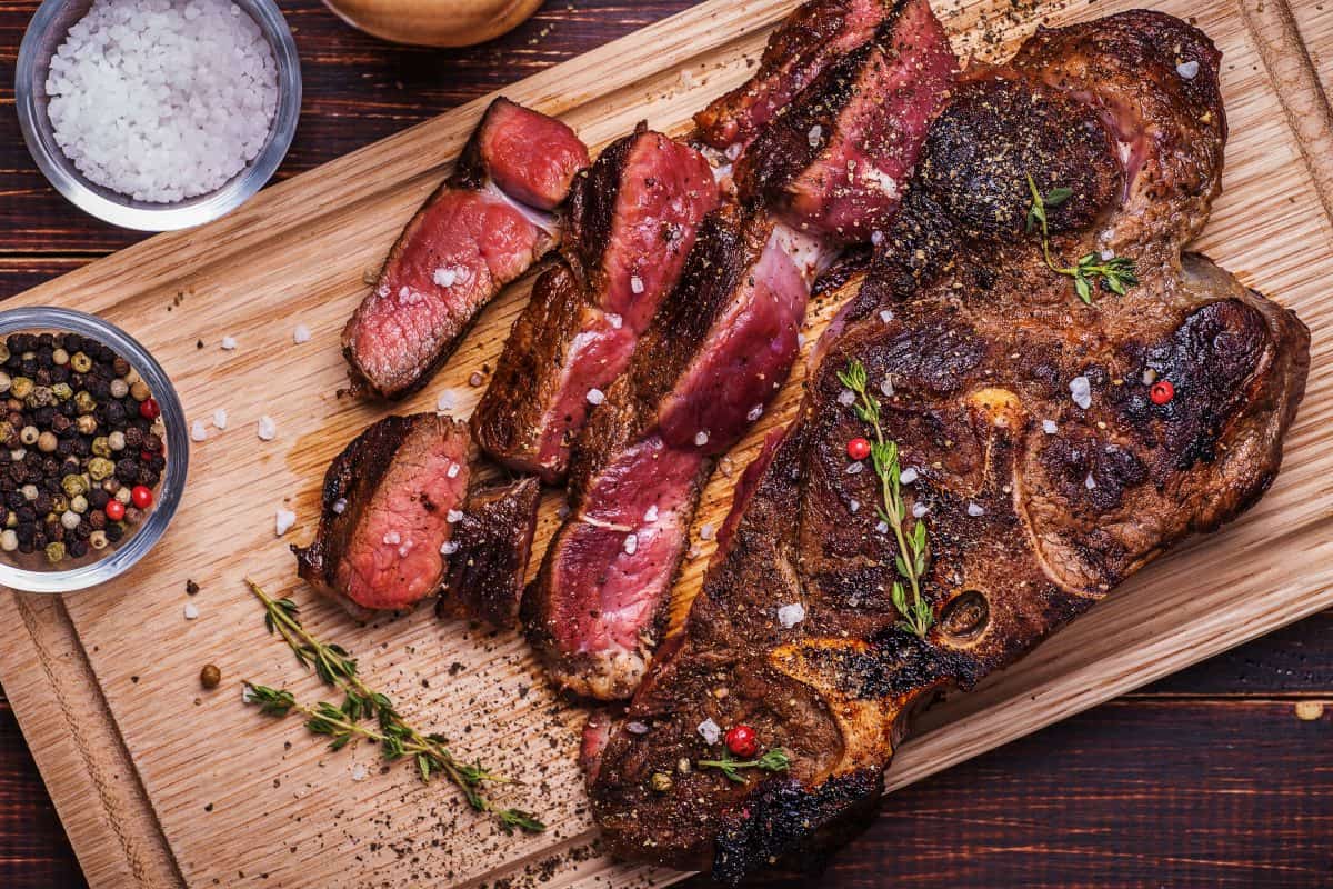 A well seared steak, partly sliced on a cutting bo.