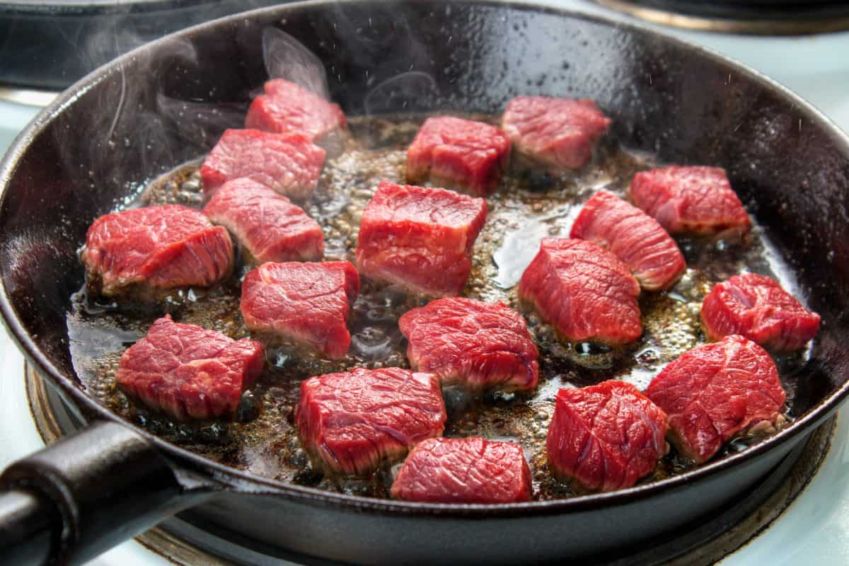 searing beef cubes in a pan on the .