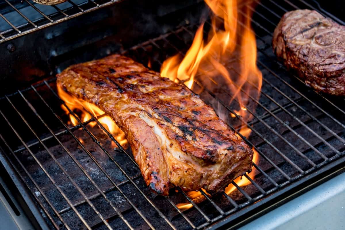 Searing a large piece of pork on a flaming hot gr.