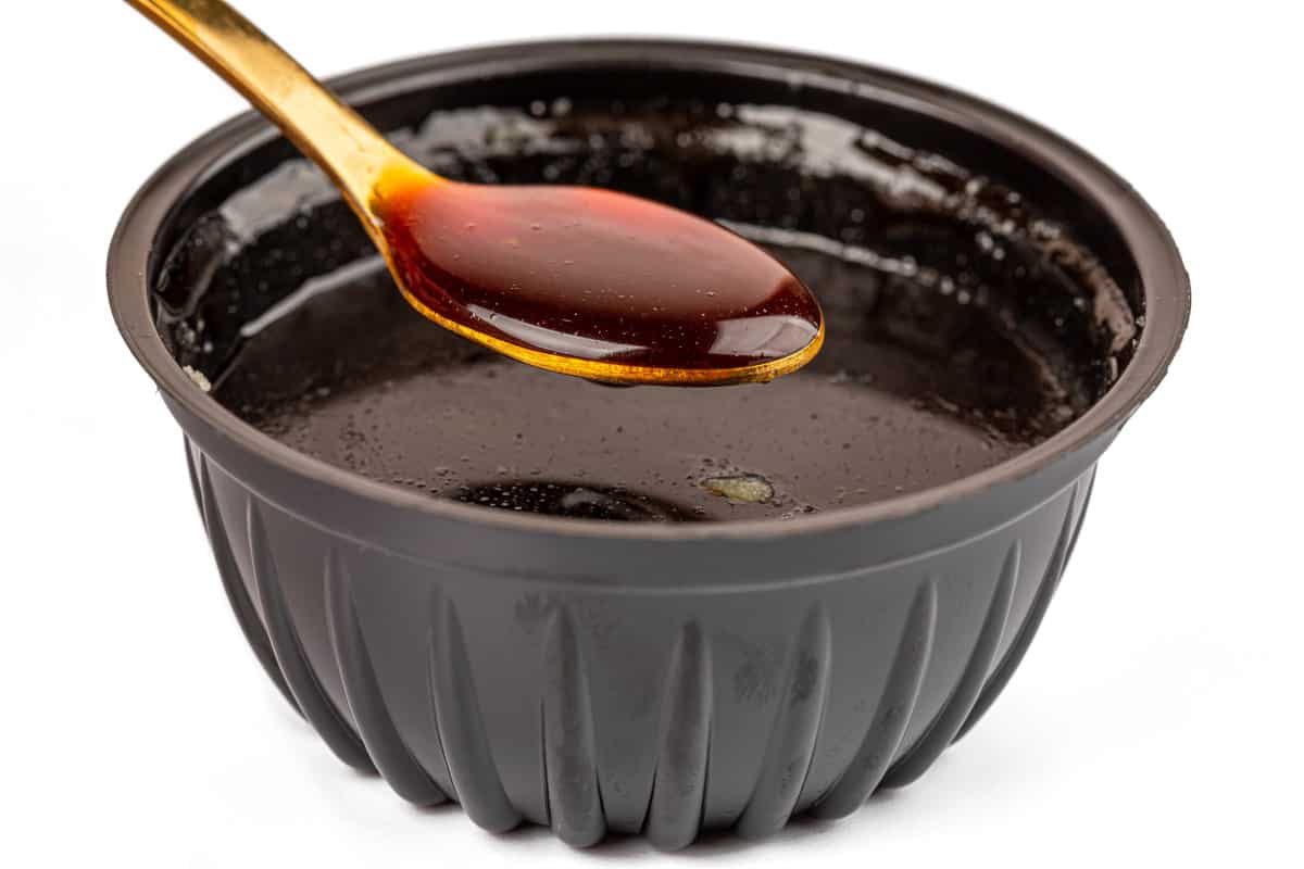 A spoon and bowl full of thick bbq sauce, isolated on wh.
