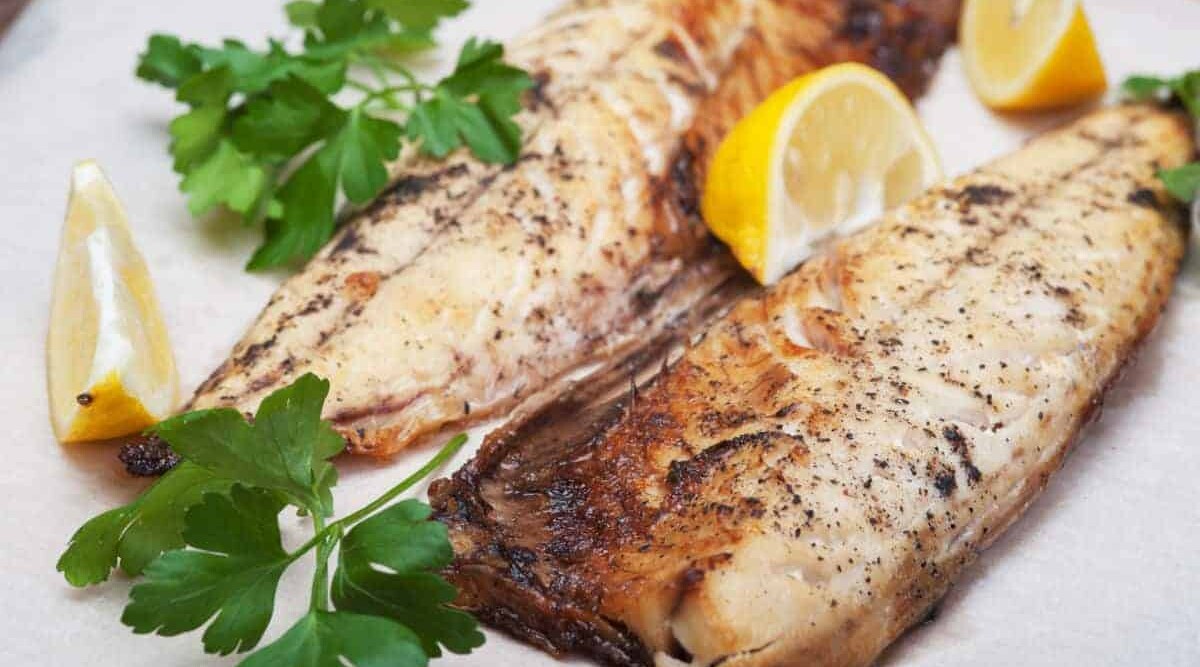 Some fish fillets on a plate with lemon after broiling to create a nice sear.