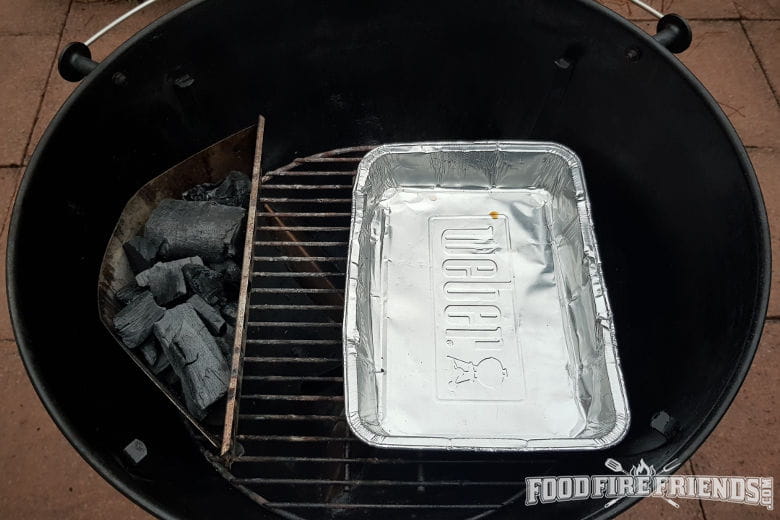 A weber ketttle grill set up for 2-zone grilling