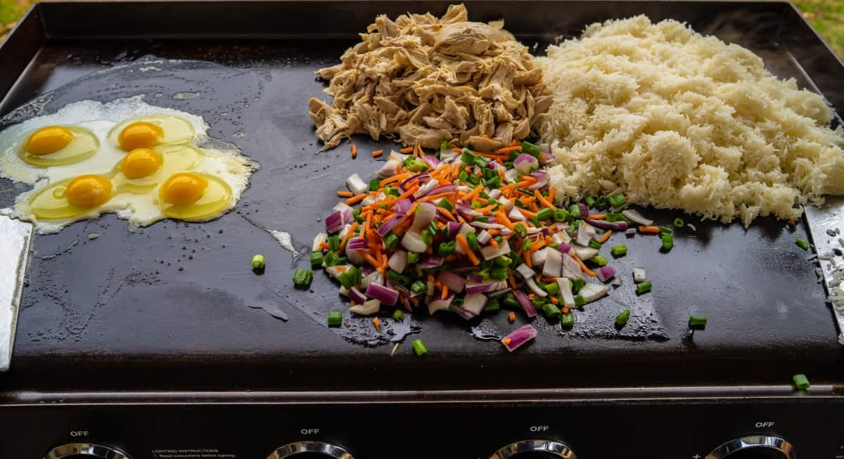 Eggs, diced veg and rice being cooked on a grid.