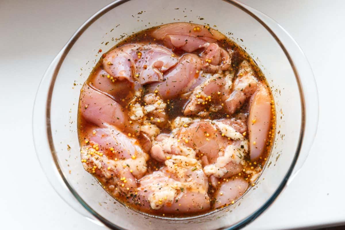 A shot from above of a bowl of chicken fillets marinat.