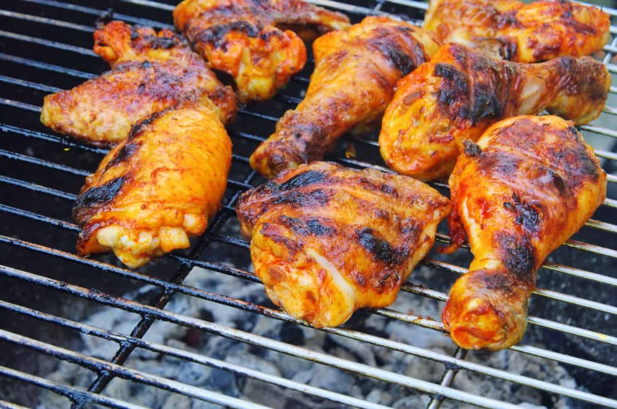 Charred, crispy chicken pieces on a charcoal gr.