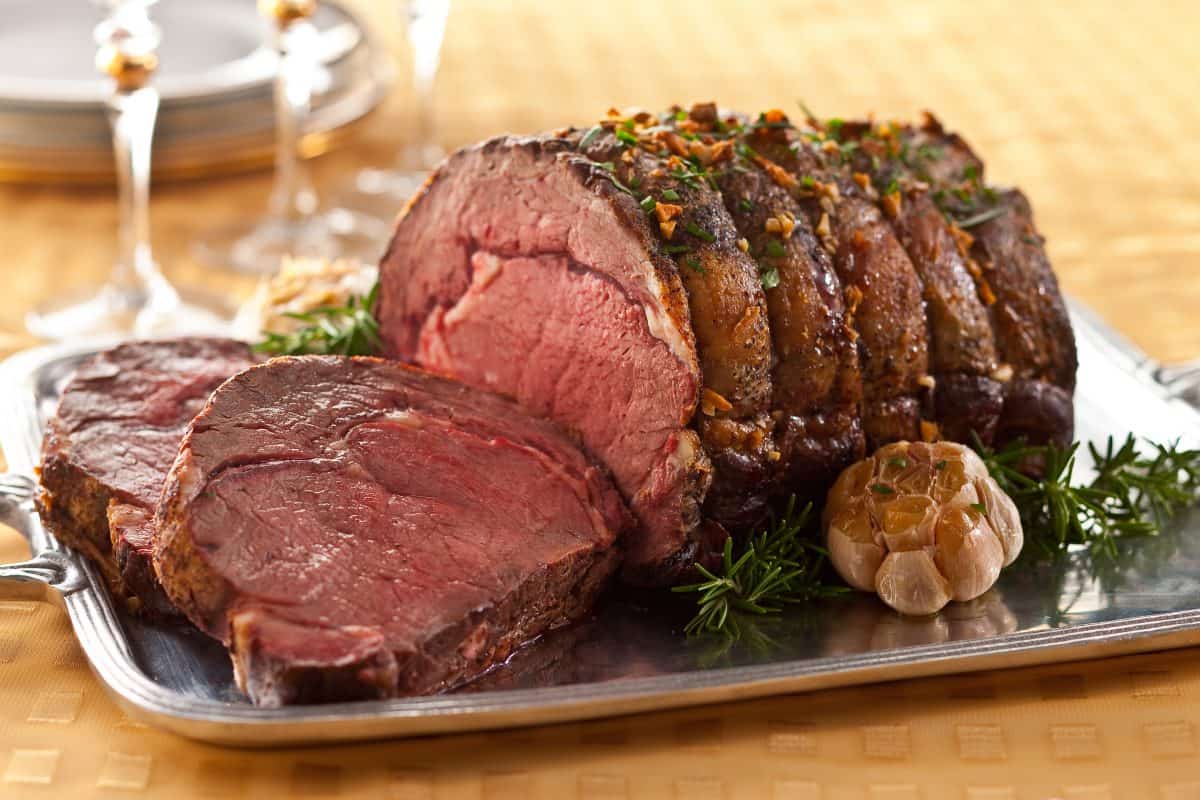 A perfectly medium-rare roasted prime rib on a serving t.