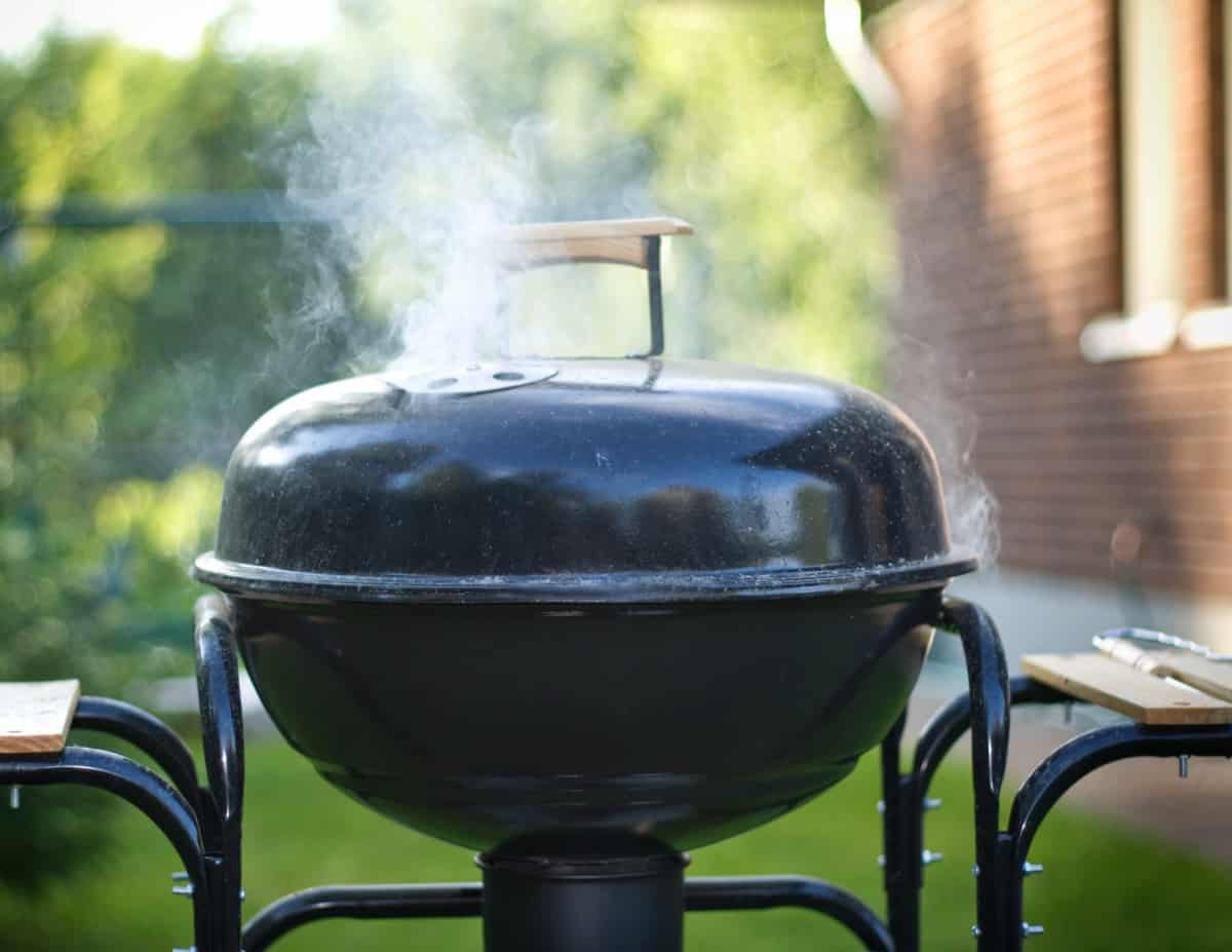 A charcoal grill with smoke coming out of .