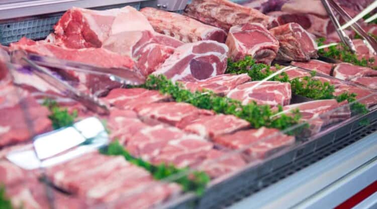 Close up, angled view of portions of meat in a counter.