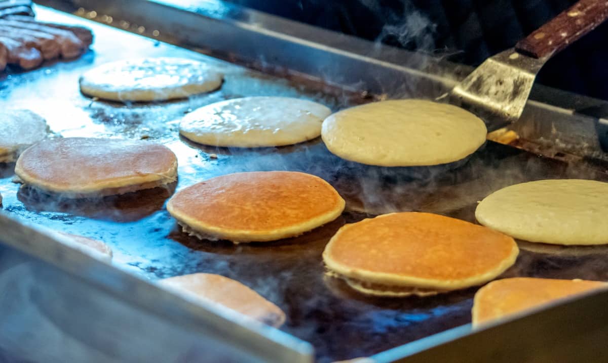 Golden pancakes being turned on a griddle