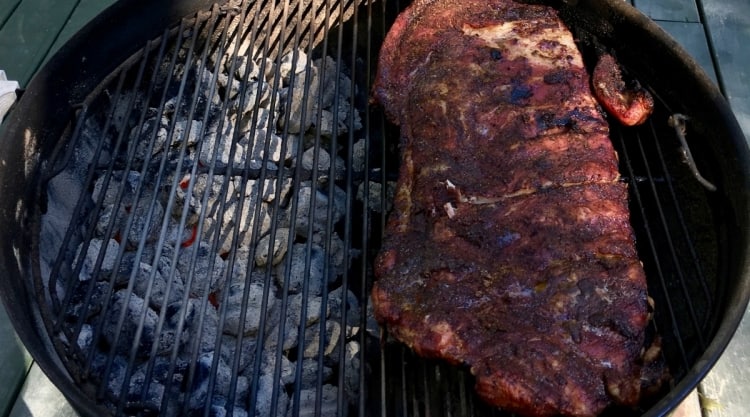 Ribs cooking indirect on a kettle style charcoal grill.