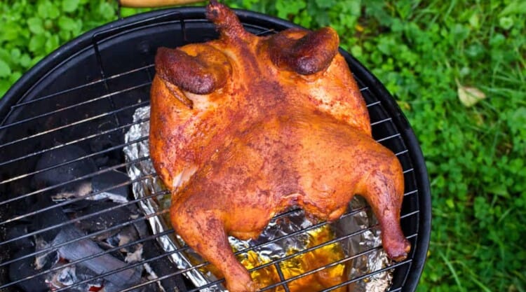 A sptachcock chicken being roasted on the grill