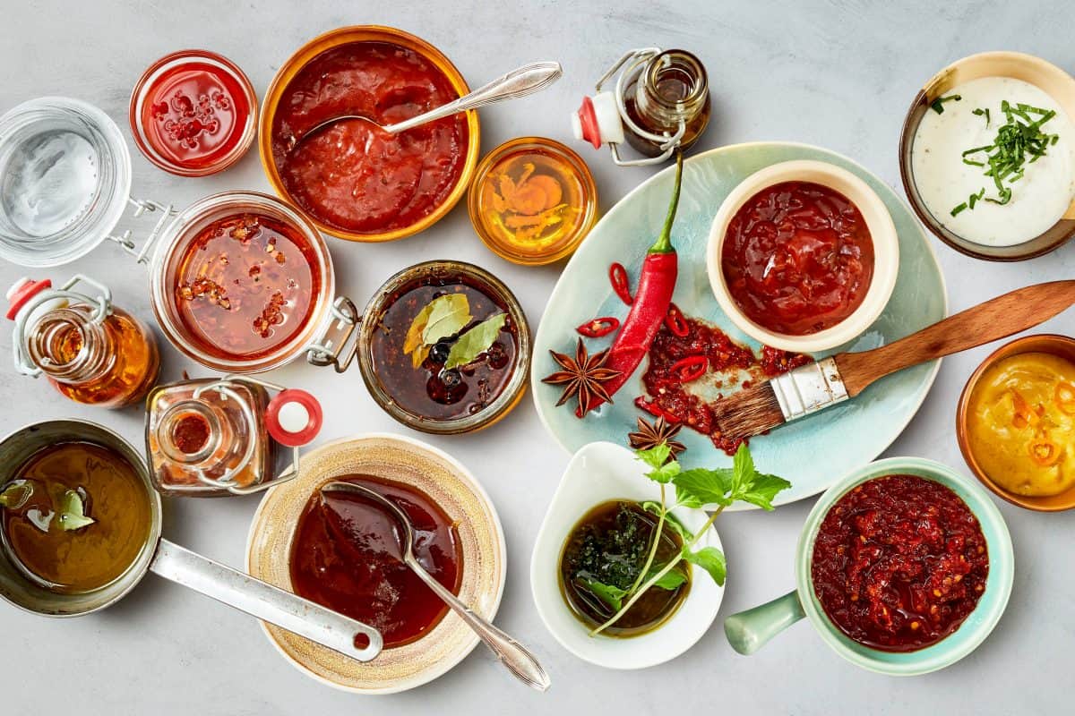 An overhead shot of a selection of marinades on a white ta.
