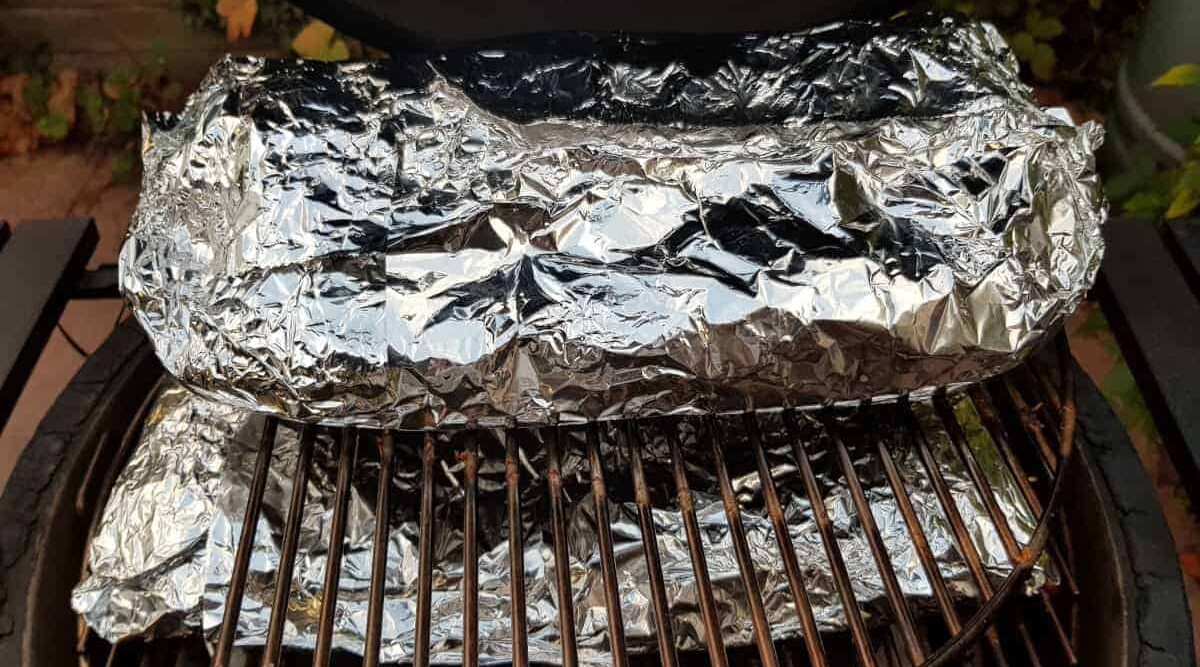 Racks of ribs, wrapped in foil and back on the grill Texas crutch style.