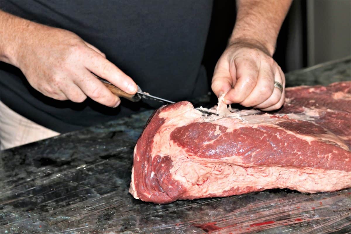 A man with a small knife trimming a bris.