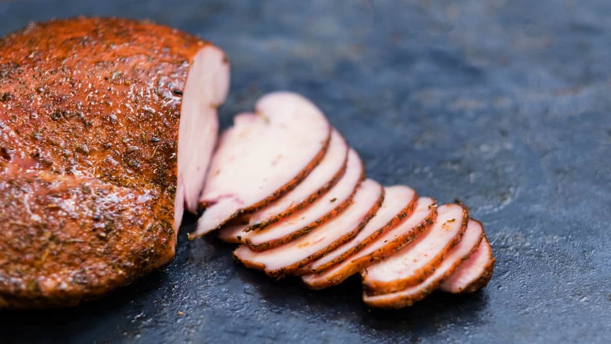 Sliced, smoked turkey breast on a dark surface