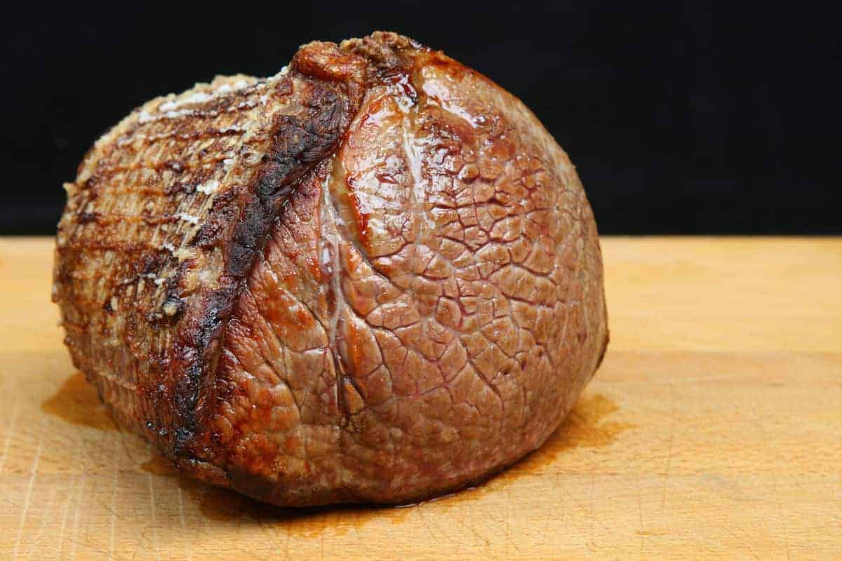 A joint of roast beef resting on a chopping bo.