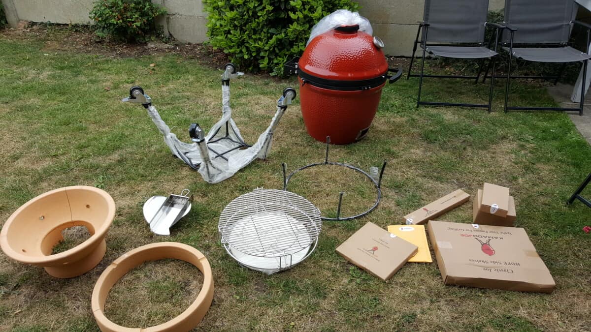 Kamado Joe version 1 parts laid out on a grass lawn, unassembled.
