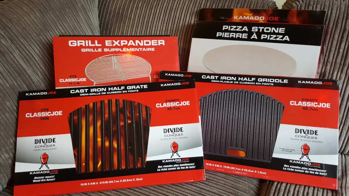 A selection of Kamado Joe accessories, still in their white and red boxes, on a chair cushion.