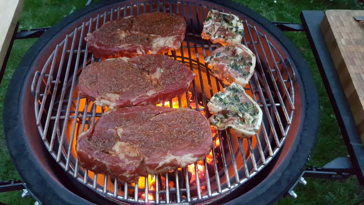 Steaks and pork chops on a Kamado Joe smoker.