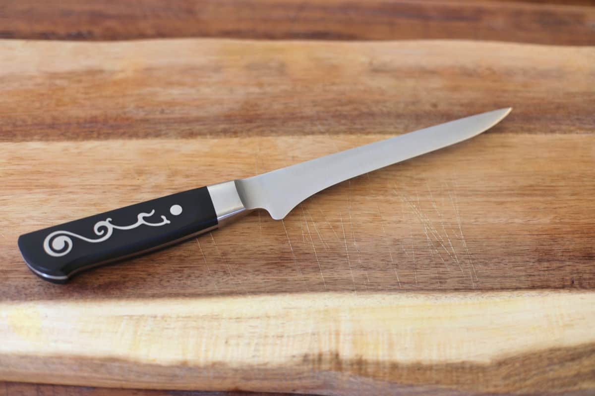 Close up of boning knife on a rustic looking wooden bo.