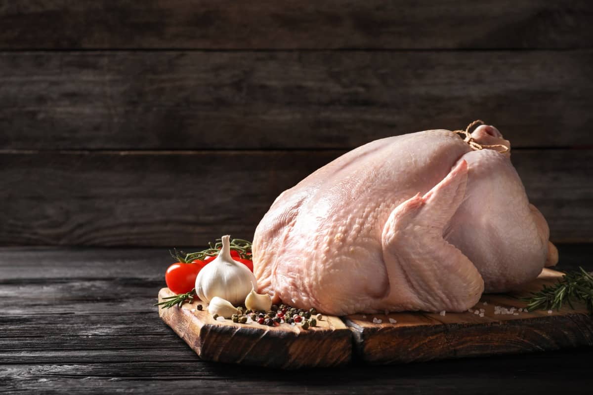 Raw turkey and other ingredients on a wooden chopping bo.