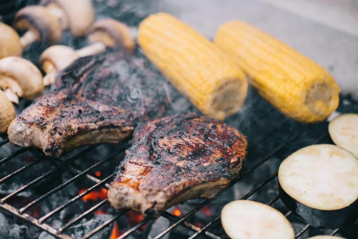 Steaks, corn and mushrooms on a hot gr.