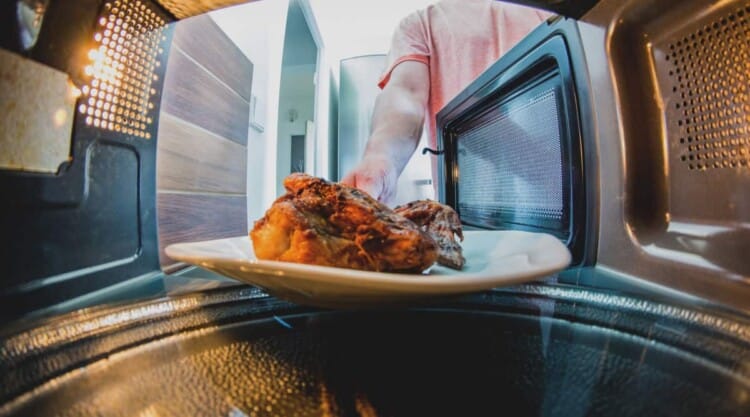 View from the inside back of a microwave, looking out over meat through the open door.