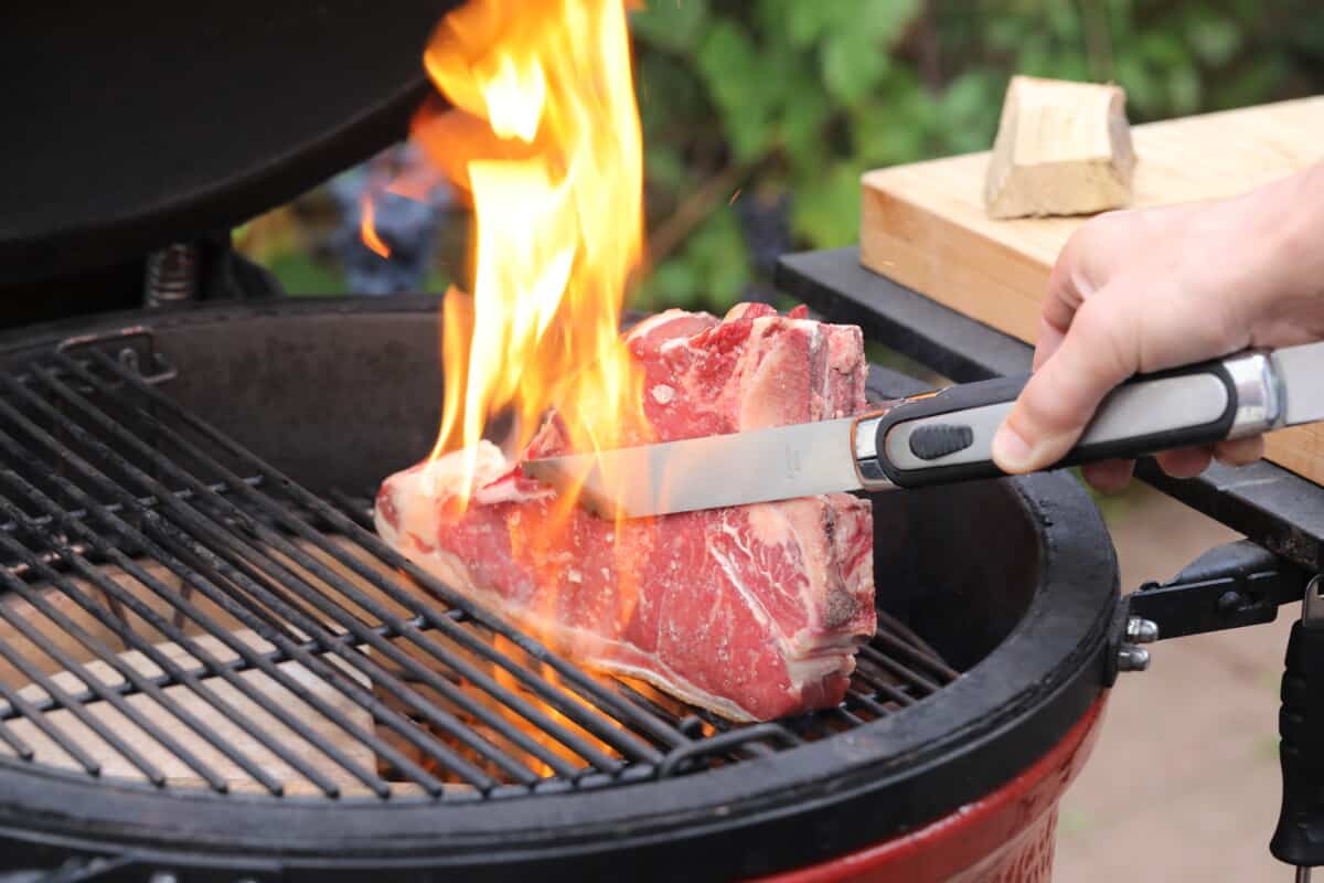 Searing a T-bone steak on a Kamado Joe grill.