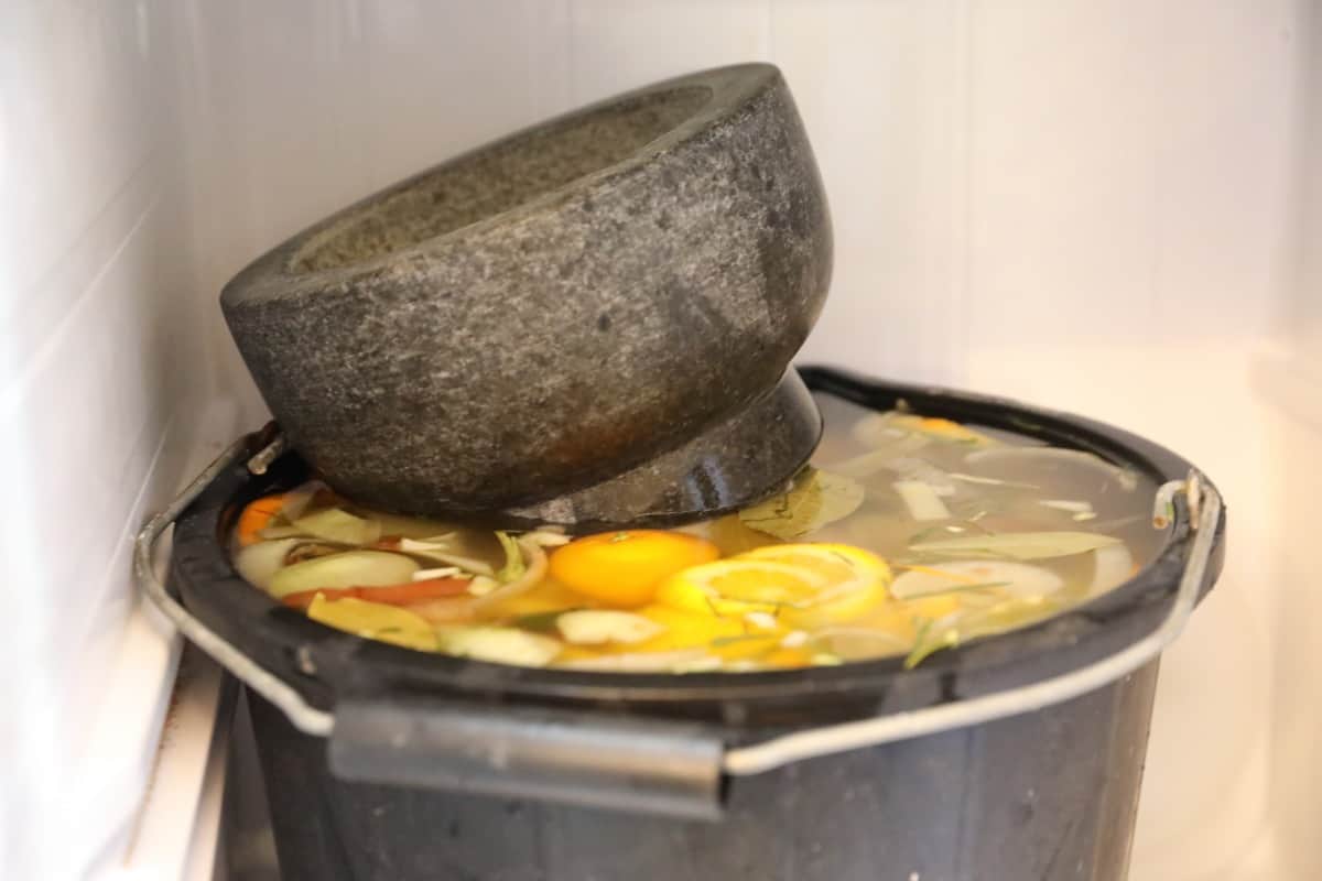 A stone pestle in a large bucket of brine, on top of a turkey to make sure it stays submer.