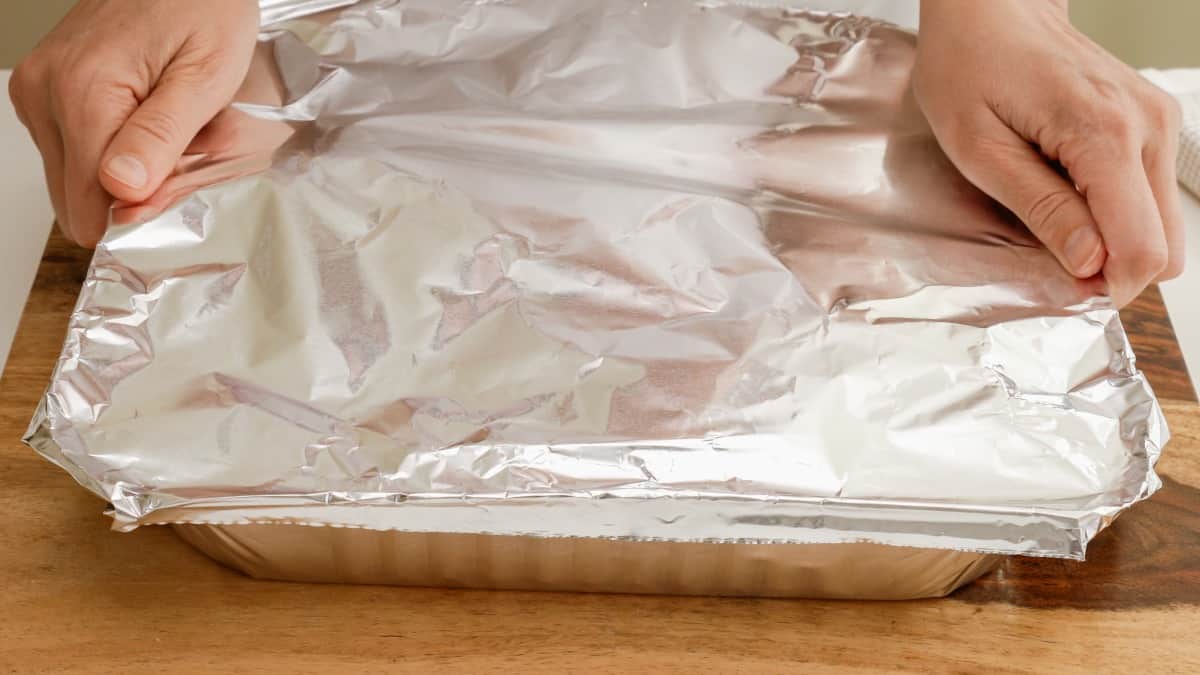  Wrapping a disposable foil tray in tin foil to seal it